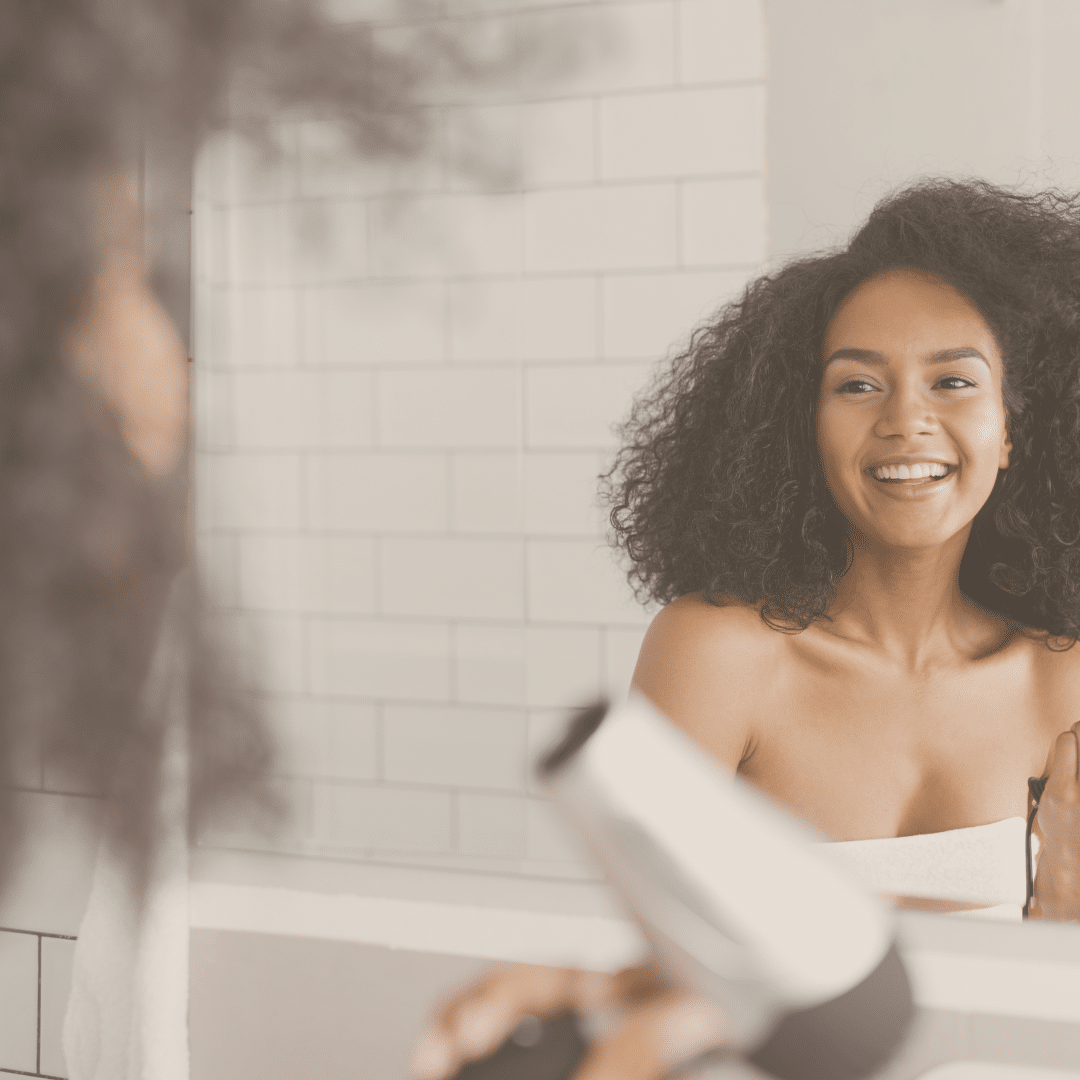 Femme utilisant un sèche cheveux, mauvaise habitude qui contribue aux cheveux gras.